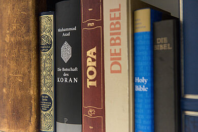 Buchregal mit den verschiedenen Büchern bzw. heiligen Schriften nebeneinander